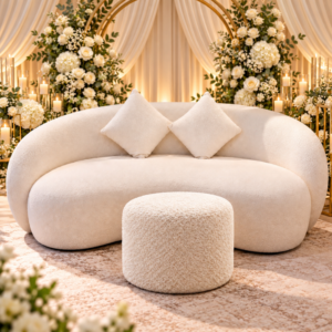 Curved cream bridal sofa with cushions in a floral wedding setting